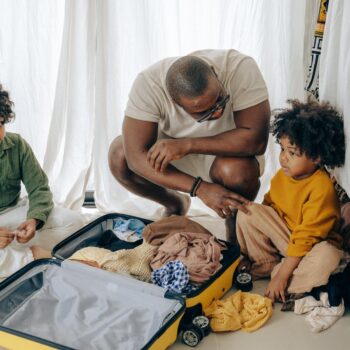 african american father with kids sitting near suitcase