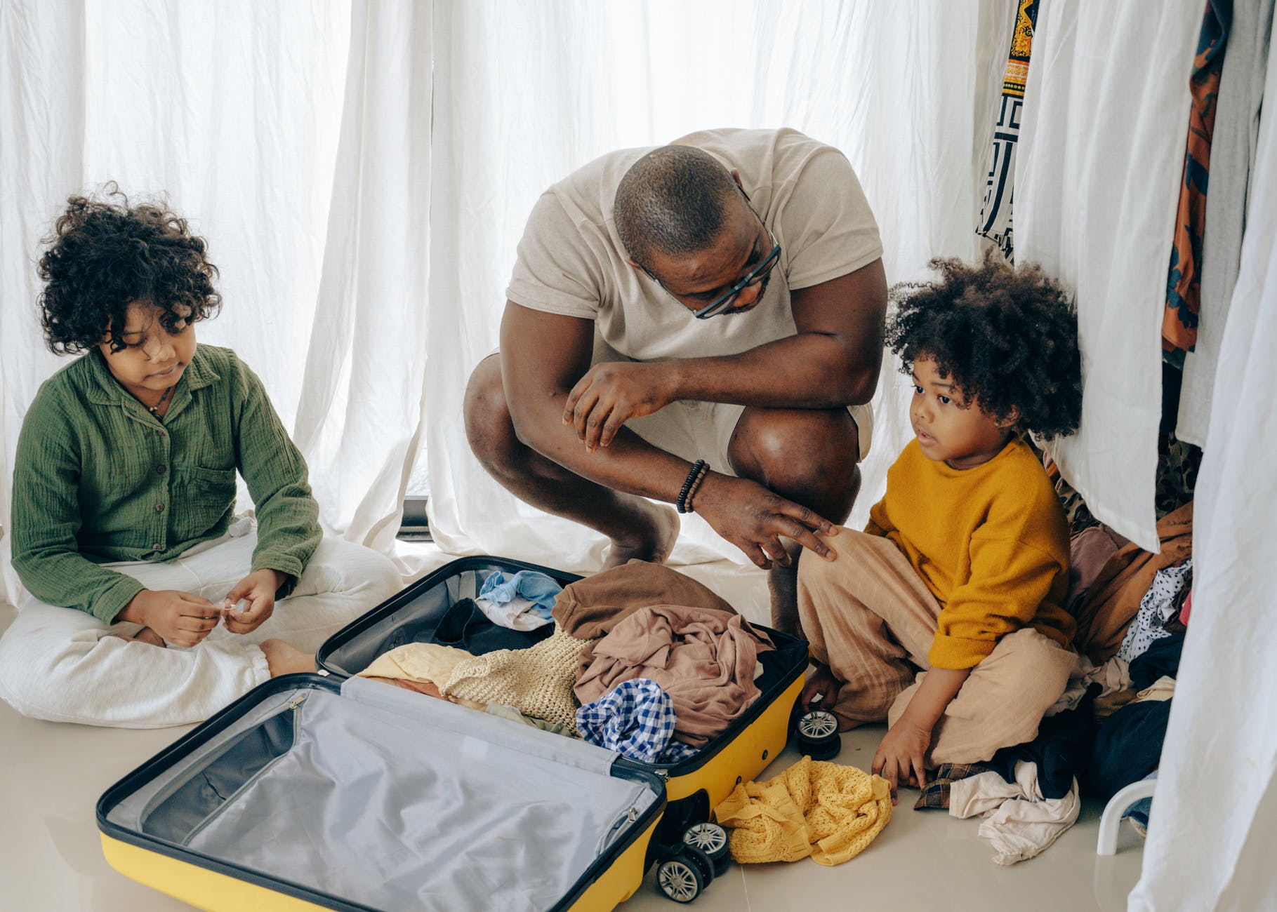 father with kids sitting near suitcase