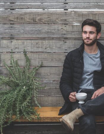 man sitting on bench having a cup of coffee