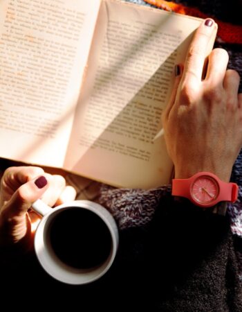 person reading book and holding coffee