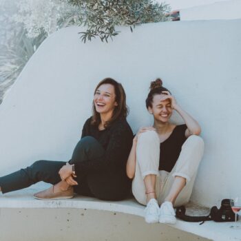 two women sitting on white bench