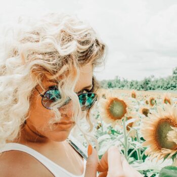 woman wearing sunglasses on sunflower field