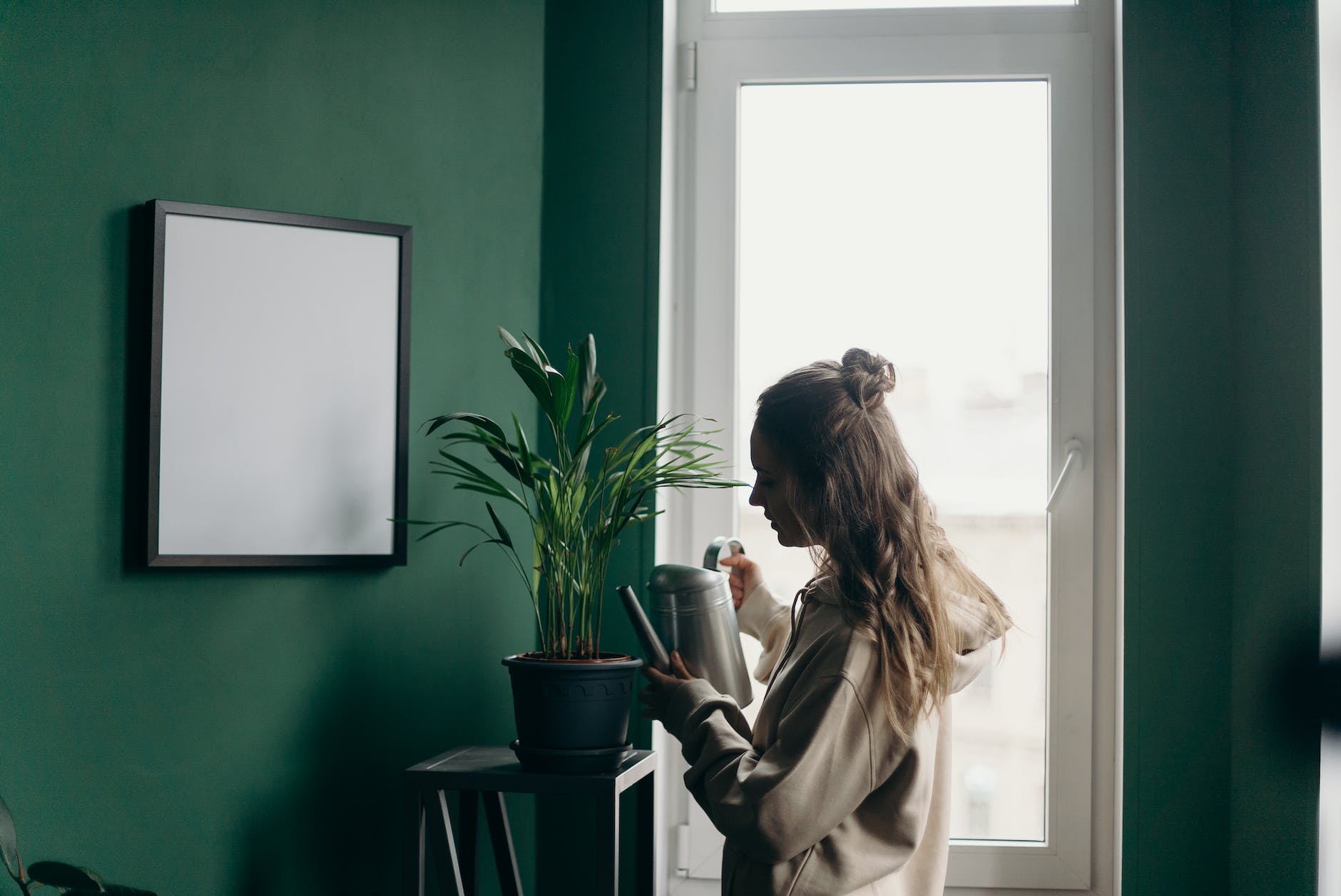 woman in beige coat standing near green wall